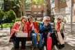 © Westend61 - Fashionable women laughing together while shopping outdoors in urban park