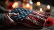 © Nytheris  - Close-up of Hands Holding American Flag with Poppy Tribute and Candles in Soft Light