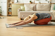 © LIGHTFIELD STUDIOS - Senior woman practices yoga on a mat in a cozy living room during morning light