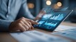 © Papisut - Businessman reviewing quarterly financial report with tablet and graphs AI technology concept
