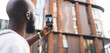© BullRun - African American man taking vertical photo of smart building with smartphone, representing mobile photography, digital immersion, and interaction with urban environment through tech.