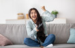 © Prostock-studio - Full length fo excited Indian woman with joystick sitting on couch at home, making victory gesture, winning in video game. Young lady playing online computer arcade, having fun during covid lockdown