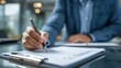 © khumthong - Close up of a person's hand meticulously filling out a checklist form with a pen on a clipboard in an office setting