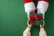 © ActionGP - Santa Claus presents a festive green gift box to a child with a joyful holiday spirit