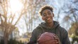 © Valeriia - African American teenage boy smiling while holding a basketball outdoors in a sunlit park, surrounded by trees and a vibrant atmosphere, showcasing joy and youthfulness