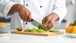 © am - Professional chef in a clean white uniform meticulously slicing fresh ripe kiwi fruit on a wooden cutting board in a bright kitchen