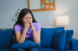 © PaeGAG - Young Asian Woman Crying While Sitting on Sofa in Living Room