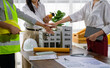© PaeGAG - Architects joining hands over building model celebrating successful project