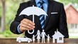 © Billing  - Businessman holding umbrella protecting family car and house icons representing insurance concept