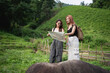© WMSTUDIO - Two young women exploring nature, studying a map together in a lush green rural landscape, enjoying adventure and friendship outdoors