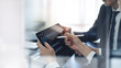 © tippapatt - Businessman having a discussion with colleague, working together in office. Two asian business people using digital tablet at meeting. teamwork and collaboration