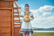 © 亮亮 徐 - A Mongolian girl wearing Mongolian attire and holding a bucket of milk tea in front of a yurt.