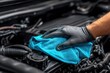 © Ilham - Close-up of a hand in black glove wiping a car engine with a light blue cloth
