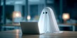 © Tondo - Ghost in white sheet using laptop in dark office