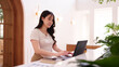 © snowing12 - Asian adult woman freelance business professional remote working online using laptop computer at modern bright cafe for productive workflow