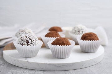 Wall Mural - delicious homemade candies with cocoa powder and coconut flakes on light grey table, closeup