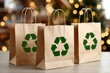 © Moopingz - Three brown paper shopping bags with green recycle symbol, placed on table with blurred festive lights in background.