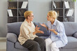 © Studio Romantic - Elderly mother and adult daughter sitting on couch, engaged in emotionally charged discussion, having disagreement and emotional strain. Generational conflict, relationship struggles, family tension