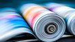 © Kanomaoi - A dynamic scene of colorful, printed paper exiting the high-speed rollers of a printing press.