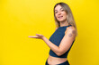 © luismolinero - Young Rumanian woman isolated on yellow background presenting an idea while looking smiling towards