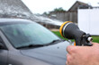 © Krystsina - Young tall man spalshing his silver car by garden hose