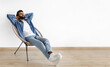 © Prostock-studio - Relaxed young Indian man relaxing with hands behind head in armchair indoor, enjoying comfort and rest on chair near white studio wall. Panorama with empty space for text advertisement