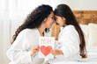 © Prostock-studio - Happy mom and cute little daughter having beauty day together, celebrating Mothers Day at home, wearing bathrobes and bonding on bed. Cheerful girl resting with her beautiful mom in hotel