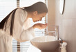 © Prostock-studio - Long-haired young chinese woman in silk bathrobe washing face in the morning after waking up, beautiful bathroom interior, side view, copy space. Hygiene, body care, skin care concept