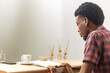 © BillOkore - African young man studying at table with coffee and notebook. Concept: modern student lifestyle, productivity, learning in cafe, academic preparation.