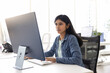 © fizkes - Focused young Indian specialist woman working at computer monitor in office open space alone, using Internet technology, professional application for job task, typing on keyboard