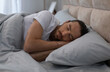 © Prostock-studio - Young man in white t-shirt is in deep sleep, lying on his side on comfortable bedding, illustrating the importance of rest in serene bedroom setting