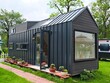 © IMRAN_IM33 - Modern tiny house with garden and brick path, showcasing sustainable living and minimalist architecture