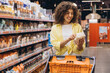 © anatoliycherkas - Woman Choosing Food in Supermarket Reading Product Label