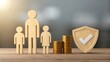 © Sajjad - Wooden family figures with stacked coins and shield symbolizing financial protection and family insurance