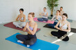 © Юлия Завалишина - Yoga mindfulness meditation. Group of sporty people doing exercise in studio for class for yoga wellness mindfulness meditation. Men women practicing yoga sitting in lotus pose meditating relaxing
