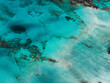 © Aerial Film Studio - Aerial view of Elafonisi Beach in Crete, Greece, showing turquoise waters, sandy shallows, and visible coral or rock formations beneath the surface.