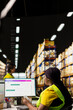© DC Studio - African american female placing adhesive shipping labels on cardboard boxes, preparing the packages for express delivery and applying awb for parcel status tracking on pc software.