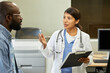© TrueFrame Collective - Portrait of beautiful Hispanic woman working as general practitioner in modern hospital consulting her African American patient