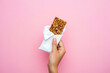 © Abdul - Enjoy healthy snack break with delicious granola bar in hand against vibrant pink background for energy boost