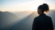 © Alexandria - Woman Seen From Behind Looking at a Mountain Vista at Sunrise.