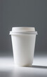 © Irwanto Labs - A clean white disposable paper coffee cup with a lid for hot beverages, shot in a studio with a plain gray background for mockup use.
