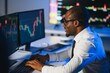 © Serhii - African american male stock trader or broker working at stock exchange office using computer