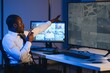 © Serhii - African American security officer or dispatch uses computer and walkie talkie, looks at screens