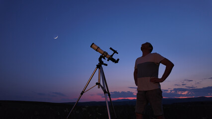 Wall Mural - amateur astronomer using telescope for watching stars, moon, planets and other celestial objects fro