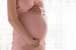 © sosiukin - Pretty young pregnant woman standing by the window in home