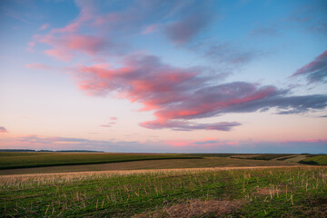 Wall Mural - Dazzling sunset over an open field with colorful clouds in the soft evening sky.