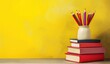 © maria - Stack of books with pencils in a vase on bright yellow background, featuring copy space for back to school or educational themed designs