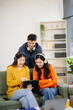© laddawan - Group of young Asian students working on a project with laptops and tablets. Cozy indoor setting,