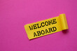 © Emre Akkoyun - Welcome aboard message written on ripped torn yellow paper piece on pink background. Conceptual welcome aboard symbol. Copy space.