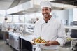 © RMedia - Smiling chef in professional kitchen holding a plate of prepared food
